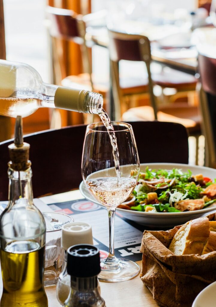 Rose wine being poured into a glass on a dining table