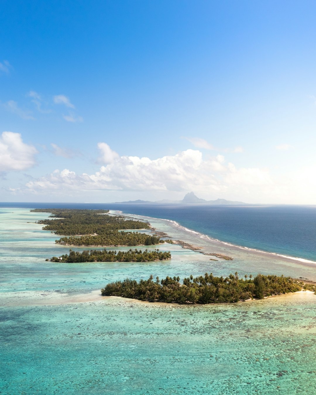 Aerial image of turquoise waters and reef break near small islands